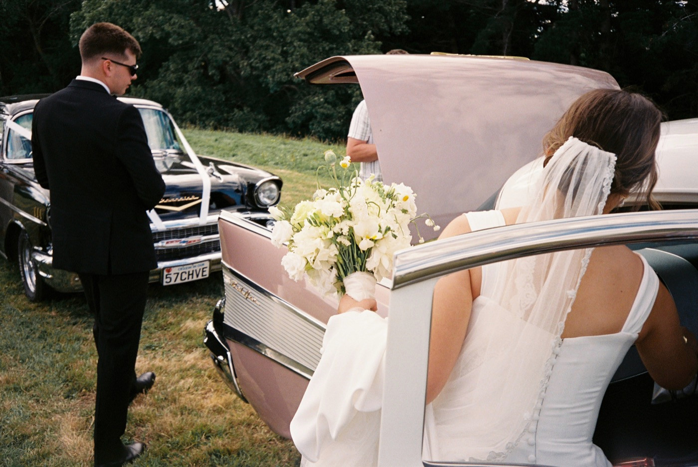 35mm film photograph of a bride stepping out of a vintage car with her bouquet