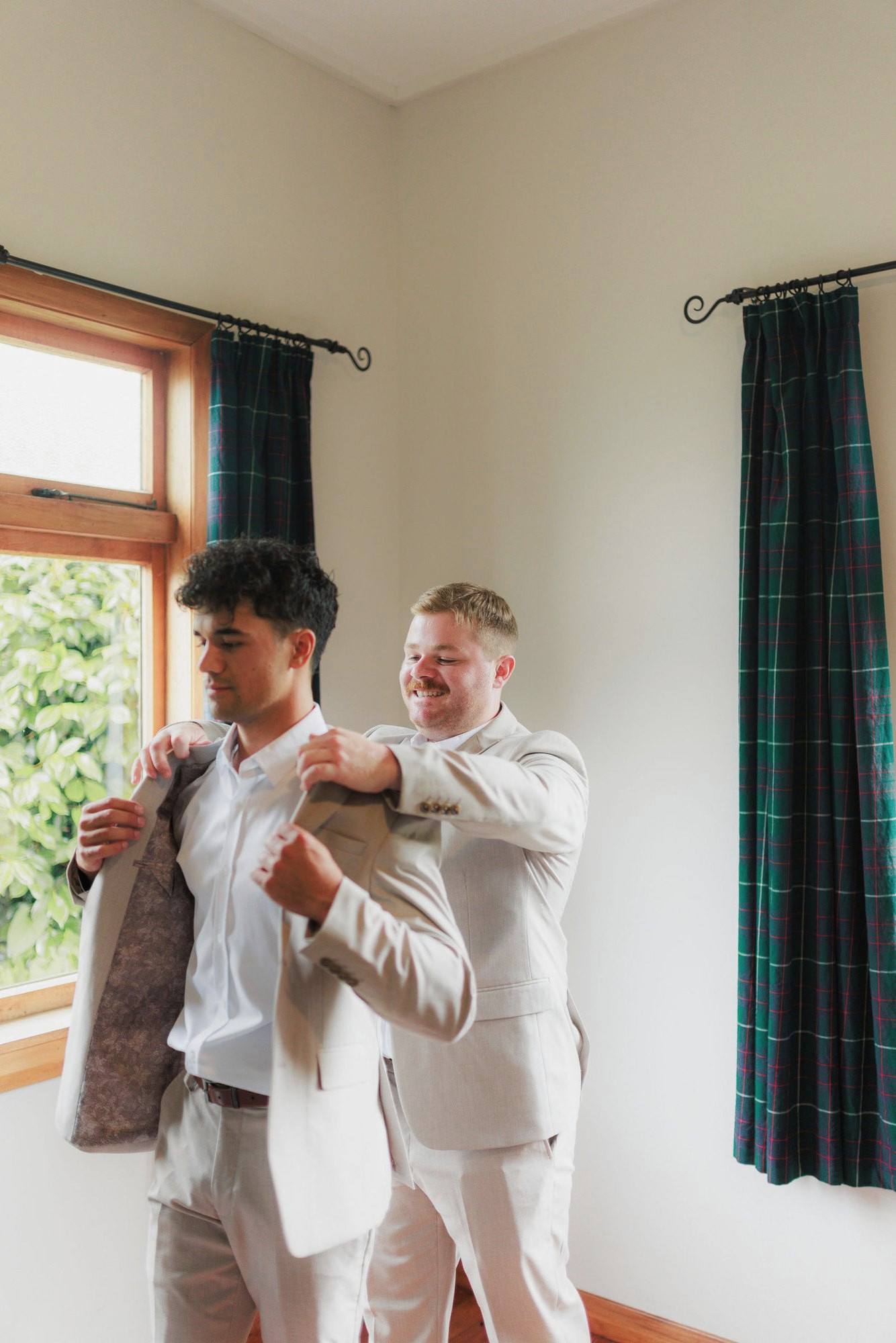 A groomsman helping the groom into his jacket