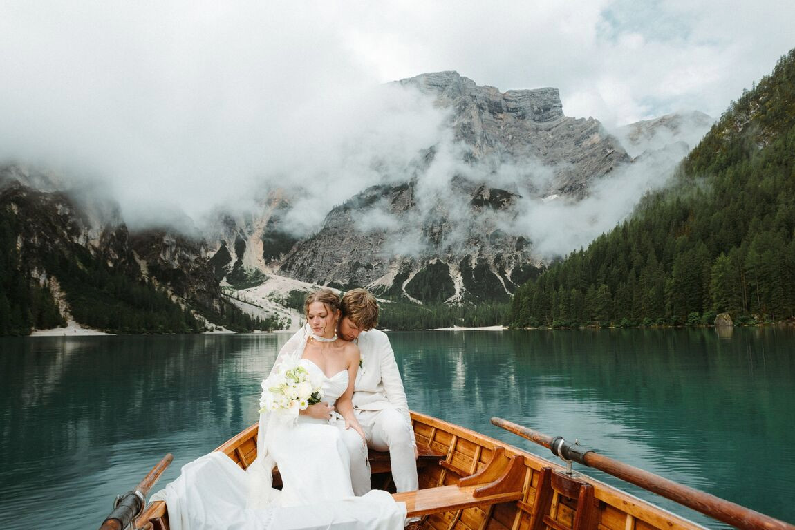 A couple in a wooden boat on a misty mountain lake